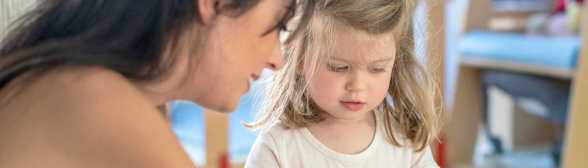 Une professionnelles de la petite enfance et une enfant qui joue