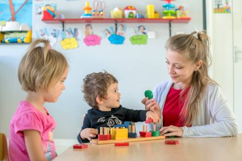 professionnelle de la petite enfance et deux enfants en train de faire des activités